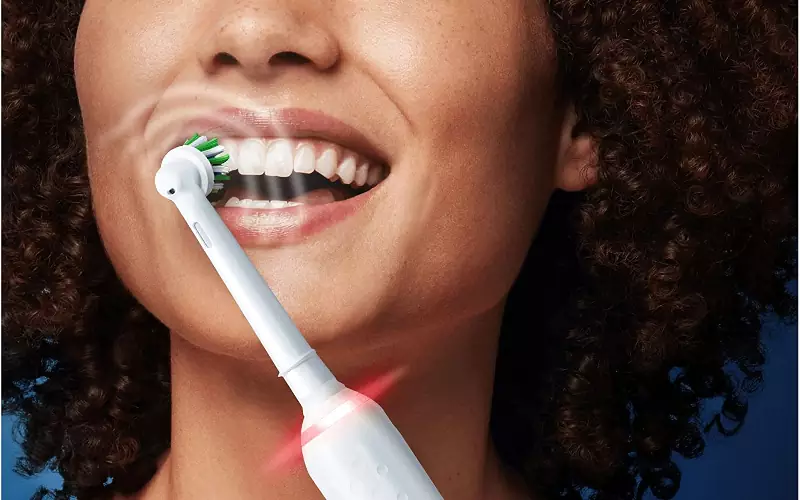 Igiene orale con uno spazzolino elettrico a testina rotante.